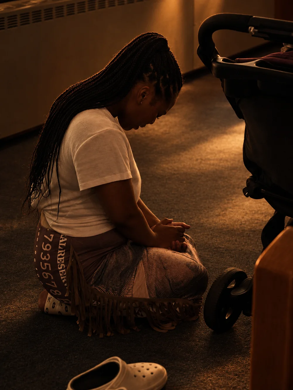 Minister Cambrelle Patterson kneeling in prayer in warm afternoon light